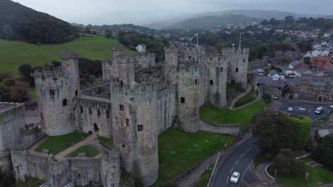 Medieval-Conwy-castle-walled-market-town-misty-mountains-aerial-view-pull-away