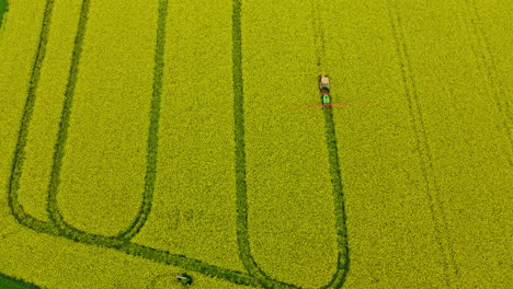 Drone-Flight-Above-Canola-Field-In-Poland-when-Farm-Tractor-Sprayer-Spraying-Fungicides-and-Pesticides,-Insecticides,-aerial-view