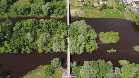 AERIAL-Fly-Over-a-River-with-a-Bridge-in-a-small-town-Ukmerge,-Lithuania
