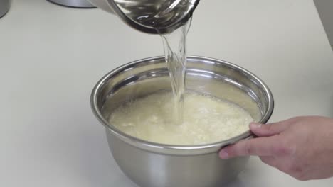 Close-up-of-adding-water-to-flour-while-making-fresh-bread-dough