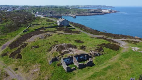 Abandoned-Amlwch-coastal-countryside-mountain-house-aerial-view-overlooking-Anglesey-harbour-rising-slow