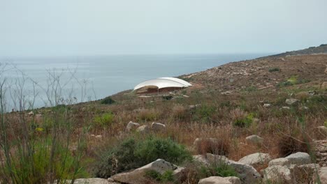 Mnajdra-megalithic-temple-complex-outdoor-on-a-cloudy-day-near-the-ocean-water-on-the-island-of-Malta,-Static-shot
