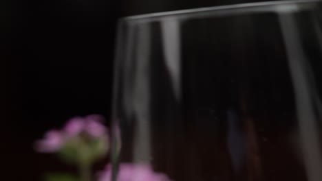 Abstrakte-Weinglas-Nahaufnahme,-Vorbei-An-Blumen-Auf-Schwarzem-Hintergrund