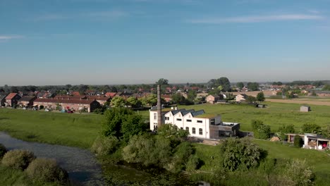Fluss-Ijssel-Landschaft-Luftaufnahme-Von-Ijsselstroom-Ehemaliges-Industrielles-Wasserwirtschaftsgebäude-Mit-Dem-Viertel-De-Hoven-Und-Glashäusern-In-Zutphen,-Niederlande,-Im-Hintergrund