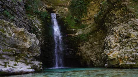Märchenhafter-Wasserfall-Mit-Sauberem-Kaltem-Wasser,-Das-In-Einen-Smaragdteich-Fällt,-Der-Von-Klippen-In-Albanien-Umgeben-Ist