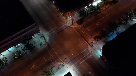A-dark-American-crossroads-with-an-expensive-sports-car-passing-through-the-video,-shot-on-the-dji-air-2