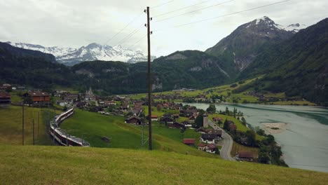 train-on-railway-at-Lake-Lungern,-swiss-alps-in-background