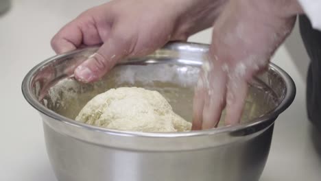 Close-up-of-hands-mixing-fresh-dough-in-a-metal-bowl