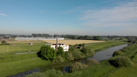 Aerial-of-former-steam-laundry-IJsselstroom-at-the-river-IJssel-with-De-Hoven-neighbourhood-and-glass-houses-in-Zutphen,-the-Netherlands,-in-the-background