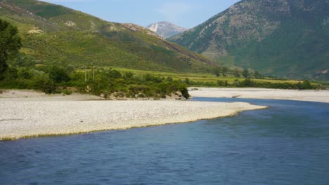 Beautiful-river-landscape-with-valley-and-mountains-background-in-lush-vegetation,-Vjosa-in-Albania