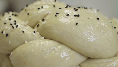 Macro-shot-of-beautifully-braided-bread-dough-as-sesame-seeds-are-sprinkled-on-top