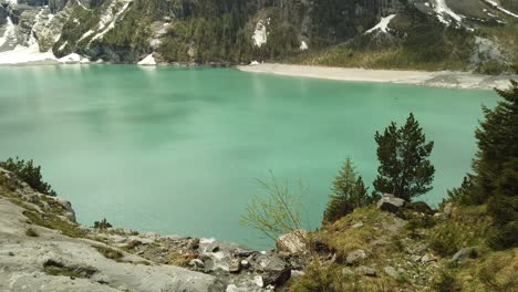 Pan-up-following-a-river-running-into-the-Oeschinensee-in-Switzerland