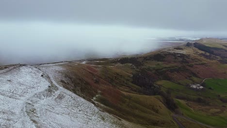 Aerial-view,-Mam-Tor,-Peak-District,-mountain,-England-snow-storm-on-horizon