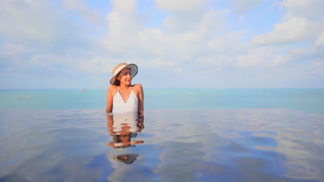 Happy-Female-With-Hat-in-Infinity-Pool-Looking-at-Skyline