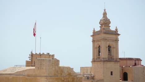 Teilansicht-Der-Kathedrale-Der-Himmelfahrt-Von-Den-Mauern-Der-Zitadella-Von-Victoria-In-Gozo-Mit-Maltesischer-Flagge