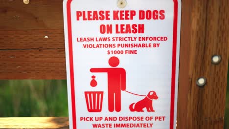 Please-keep-dog-on-leash,-laws-strictly-enforced,-violations-punishable-by-$1000-fine,-and-pick-up-your-pet-waste-poop-sign,-posted-at-public-national-park-hiking-trail