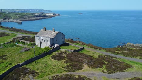 Abandoned-Amlwch-coastal-countryside-mountain-house-aerial-view-overlooking-Anglesey-harbour-slow-right-orbit-reveal