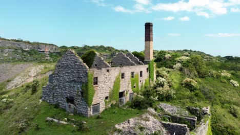 Abandoned-overgrown-ivy-covered-desolate-countryside-historical-Welsh-coastal-brick-factory-mill-aerial-view-establishing-rise-right-shot