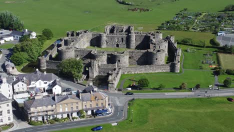 Sunny-touristic-Beaumaris-castle-town-aerial-view-ancient-Anglesey-fortress-landmark-slow-pull-back
