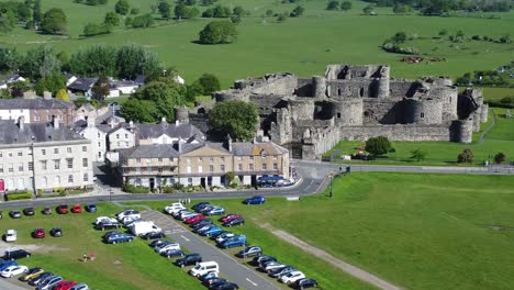 Sunny-touristic-Beaumaris-castle-town-aerial-view-ancient-Anglesey-fortress-landmark-fast-right-orbit