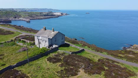 Abandoned-Amlwch-coastal-countryside-mountain-house-aerial-orbit-left-view-overlooking-Anglesey-harbour