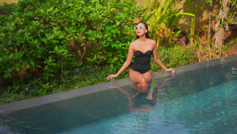 A-pretty-woman-sits-on-the-edge-of-an-infinity-edge-swimming-pool
