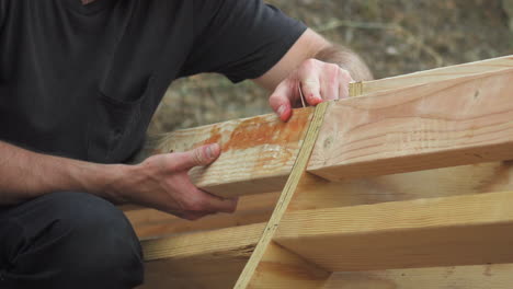 Man-Holding-Wooden-Planks-In-Place-For-DIY-Mini-Skateboard-Ramp-Project