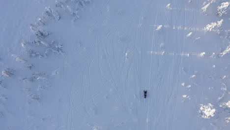 Top-view-drone-shot-of-snowmobile-rides-on-an-open-snow-field-in-Branäs,-Sweden