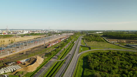 Aerial-wide-shot-showing-multiple-railroad-station,highway-and-industrial-factories-in-background