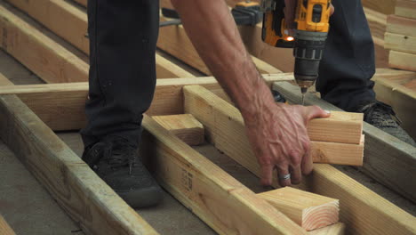 Closeup-of-Man-Drilling-Holes-Into-Wooden-Blocks-With-Power-Drill,-Unsafe-wearing-no-gloves