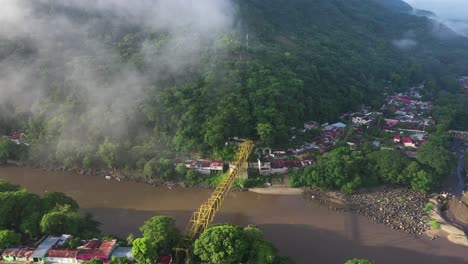 Drone-aerial-view-of-Honda,-Tolima,-Colombia,-clouds-above-valley-and-bridge-on-Magdalena-river-on-sunny-day