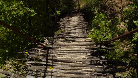 Holzhängebrücke-Mit-Ästen,-Die-über-Einem-Wilden-Fluss-Stehen-Und-Menschen-In-Den-Bergen-Albaniens-Verbinden