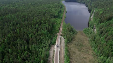 Railway-Track-Construction-And-Majestic-Boreal-Forest-With-Lake-Reveal,-Aerial-Pullback
