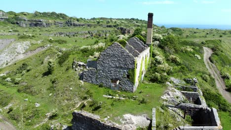 Abandoned-overgrown-ivy-covered-desolate-countryside-historical-Welsh-coastal-brick-factory-mill-aerial-view-slow-right-orbit-to-front