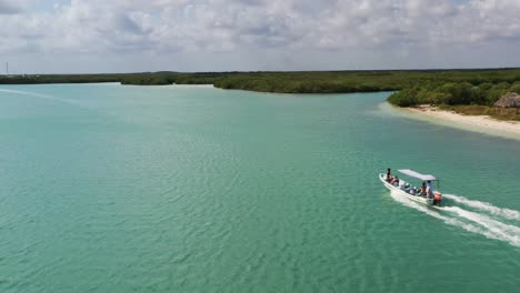 Aerial-view-video-taken-by-drone-of-boat-cruising-in-Caribbean-tropical-sand-beach-with-turquoise---sapphire-water,-Rio-Lagartos-lagoon,-Mexico