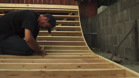 Close-Shot-of-Man-with-Drill-Building-Skateboard-Ramp-In-His-Backyard,-dolly-shot