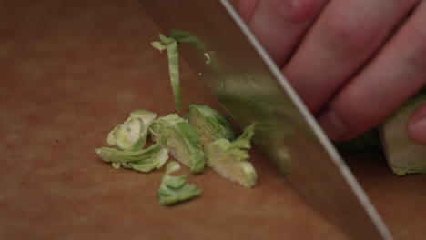 Cutting-Brussels-Sprout-With-Knife-On-Wooden-Board