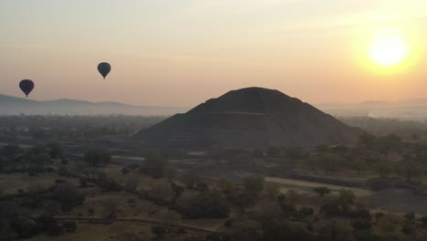 Aerial-view-of-hot-air-baloon-flying-over-Teotihuacan-Mexico-during-foggy-sunrise,-4K