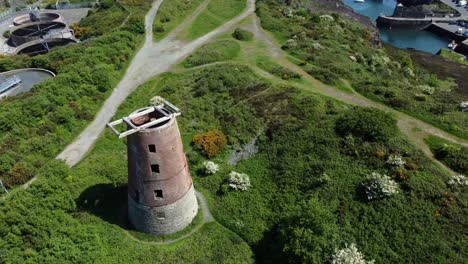 Amlwch-port-red-brick-disused-abandoned-windmill-aerial-view-North-Anglesey-Wales-tilt-up-descend-to-reveal-harbour