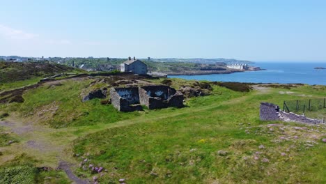 Abandoned-Amlwch-coastal-countryside-mountain-house-aerial-view-overlooking-Anglesey-harbour-descend-right