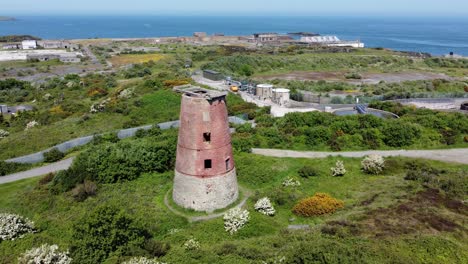 Amlwch-port-red-brick-disused-abandoned-windmill-aerial-view-North-Anglesey-Wales-slow-wide-orbit-left