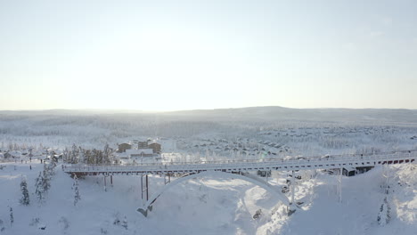 Drohnenaufnahme-Einer-Großen-Zugefrorenen-Brücke-Mit-Viel-Schnee-Während-Eines-Kalten-Wintersonnenuntergangs-In-Branäs,-Schweden