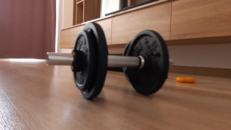 Close-up-of-dumbbells-roll-on-the-floor-in-the-living-room