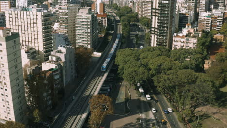 AERIAL---Belgrano-C-train-station,-Buenos-Aires,-Argentina,-wide-shot-backwards