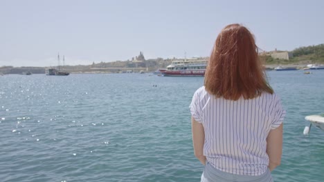 Mujer-Joven-Sentada-Y-Mirando-Los-Barcos-En-El-Gran-Puerto,-Valletta-Malta
