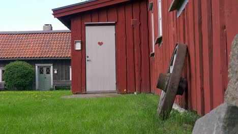 Rotes-Bauernhaus-Mit-Pferdekarrenrad-Gegen-Wand-Mit-Schwenk-Von-Rechts-Nach-Links-In-Schweden
