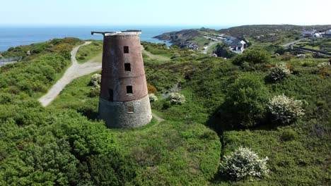 Amlwch-port-red-brick-disused-abandoned-windmill-aerial-view-North-Anglesey-Wales-slow-pull-back-reveal