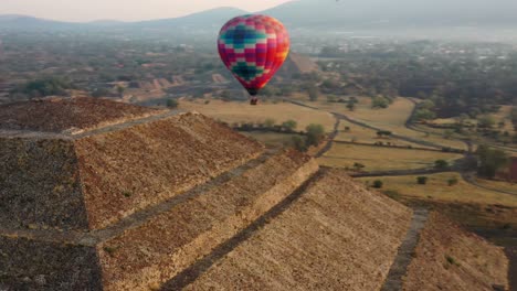 Aerial-view-of-colorful-hot-air-baloon-flying-over-the-pyramid-of-the-Aztec-culture-in-Teotihucan-Mexico-during-sunrise,-4K