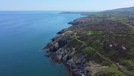 Peaceful-Amlwch-Anglesey-North-Wales-rugged-mountain-coastal-walk-aerial-rising-tilt-down-shoreline-view