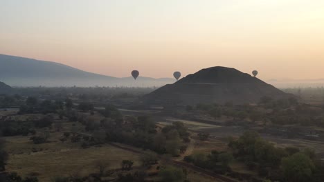 Drone-footage-of-hot-air-baloon-flying-over-Teotihuacan-Mexico-during-foggy-sunrise,-4K